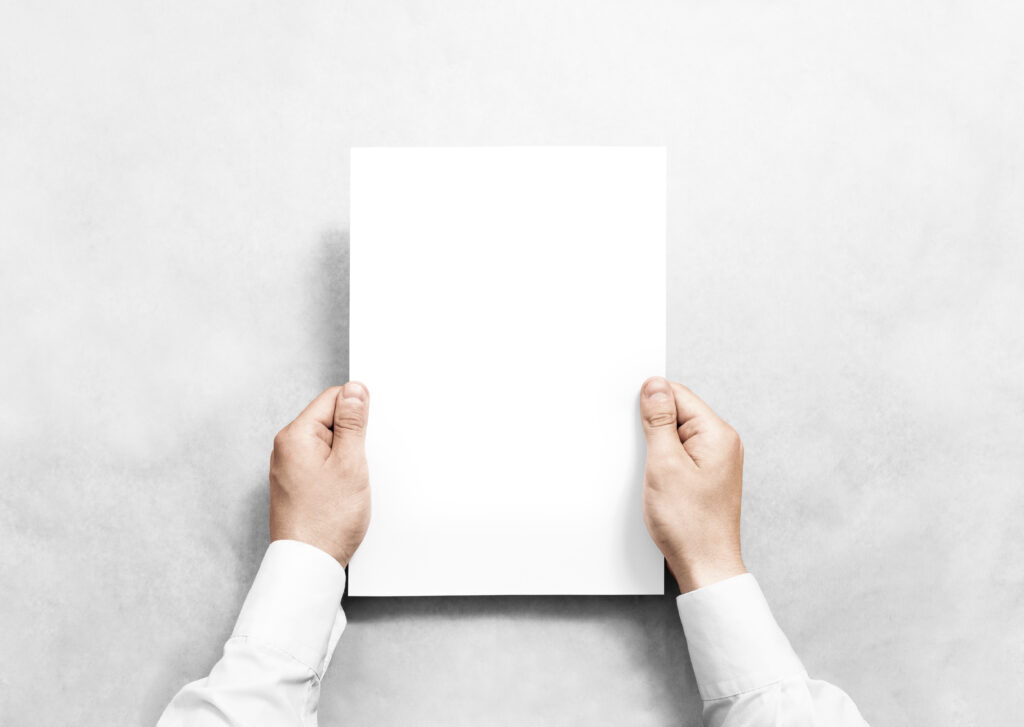Blank Document in Hands – A person in white sleeves holds a completely blank sheet of paper in front of a gray background.