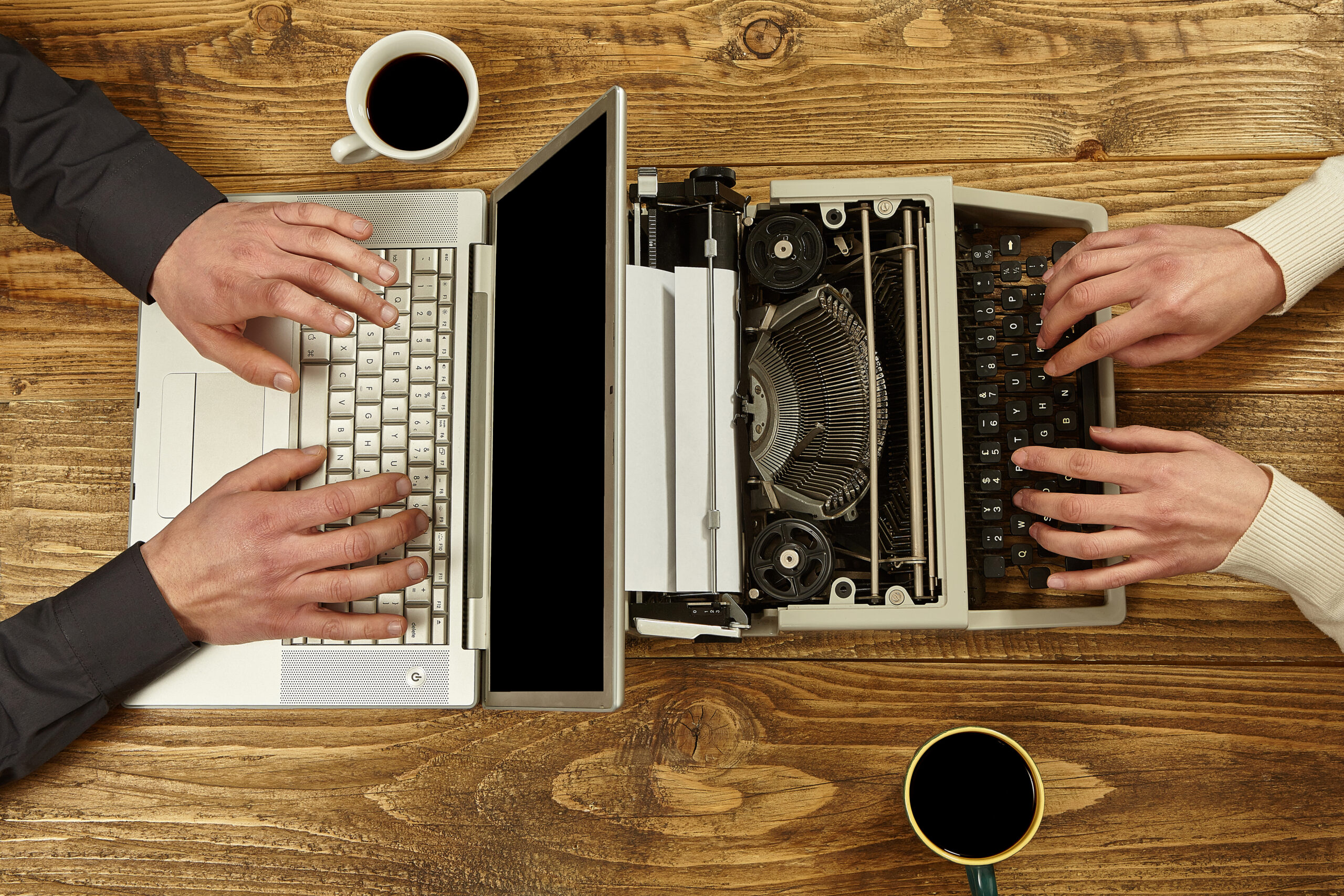 Old vs New Tech Typing – Side-by-side hands type on a laptop and a typewriter, contrasting modern and vintage tools.