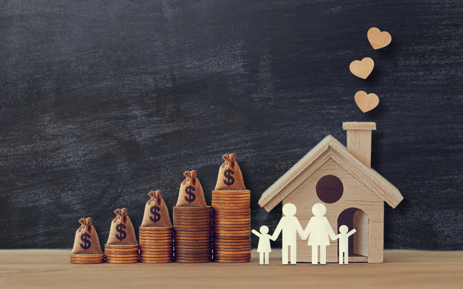 Image depicting financial security and family well-being: stacks of coins with money bags, a wooden house with a paper family cutout, and heart shapes rising from the chimney, against a dark background.